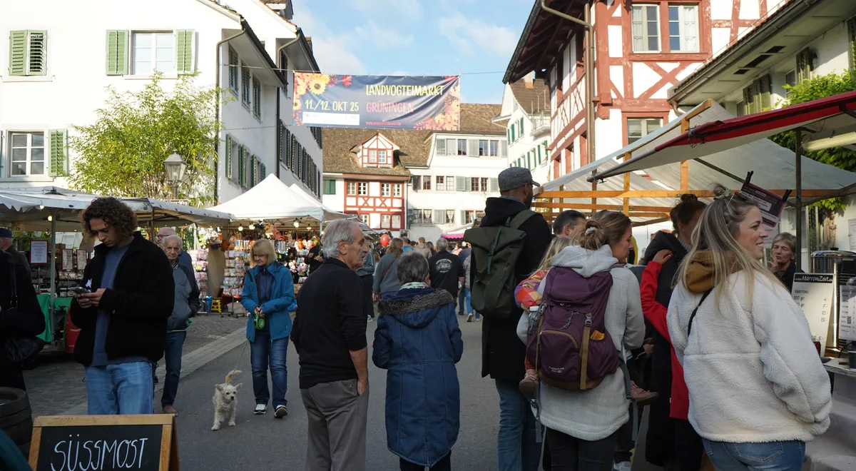 Menschen, die an einem Markt durch die Gassen schlendern. 
